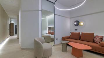 Una sala de estar moderna con sofá, sillón y mesa de centro, que presenta un espejo grande y una lámpara circular.