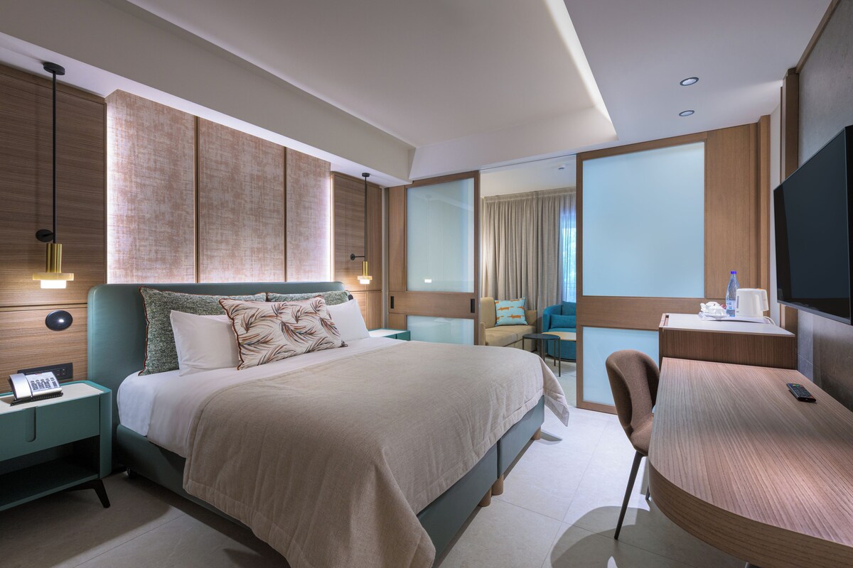 A modern hotel room with a bed, desk, and seating area.