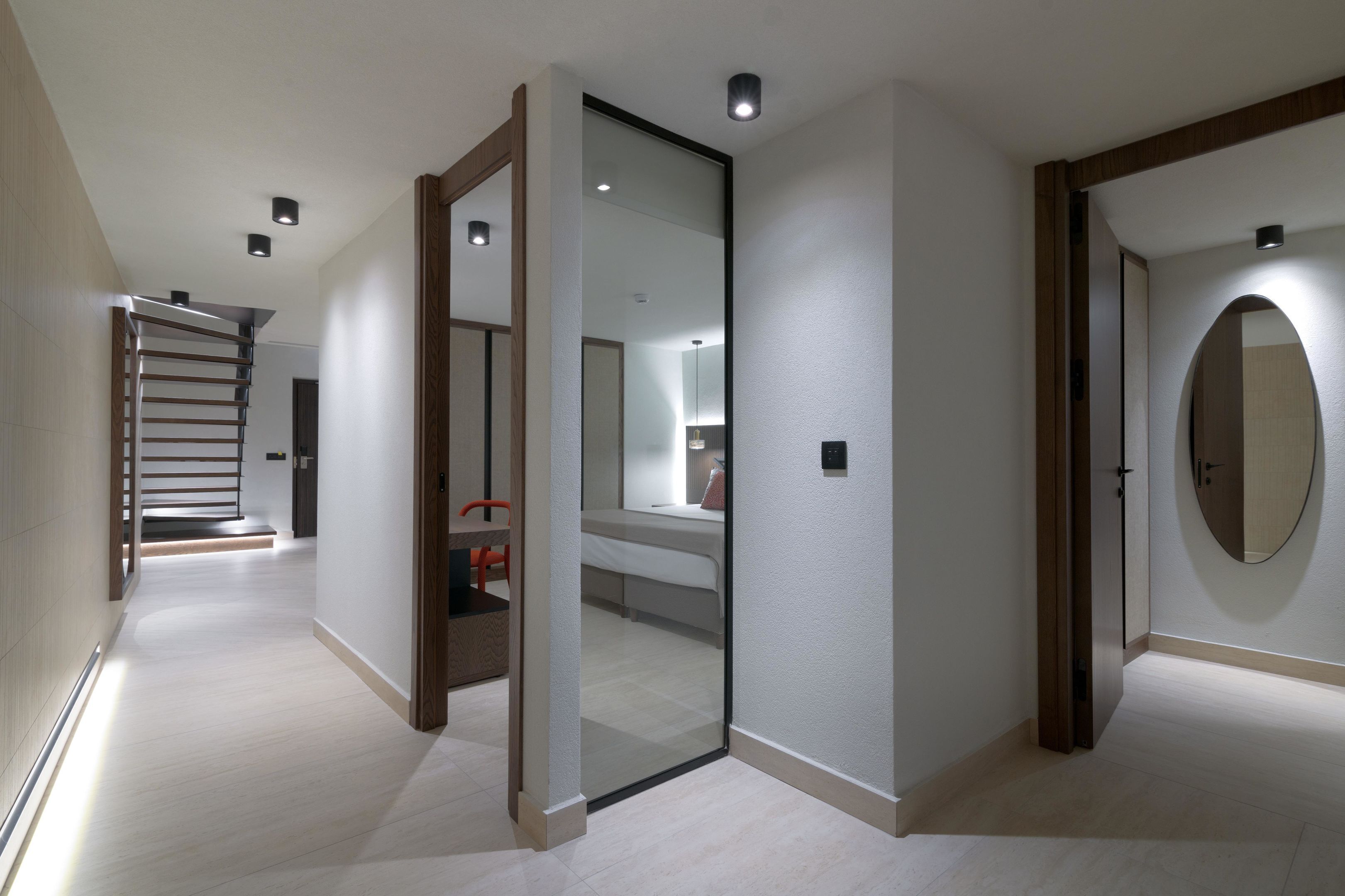 Una habitación de hotel moderna con un espejo grande, una cama y una escalera que conduce a otra habitación.