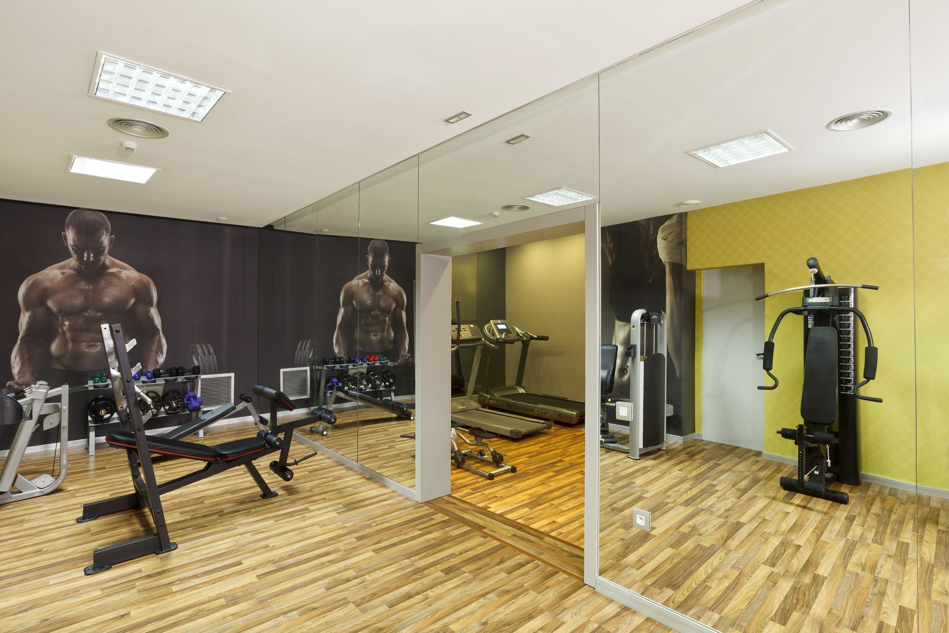 Un gimnasio con equipo de ejercicio, una cinta de correr y un muro de espejos.