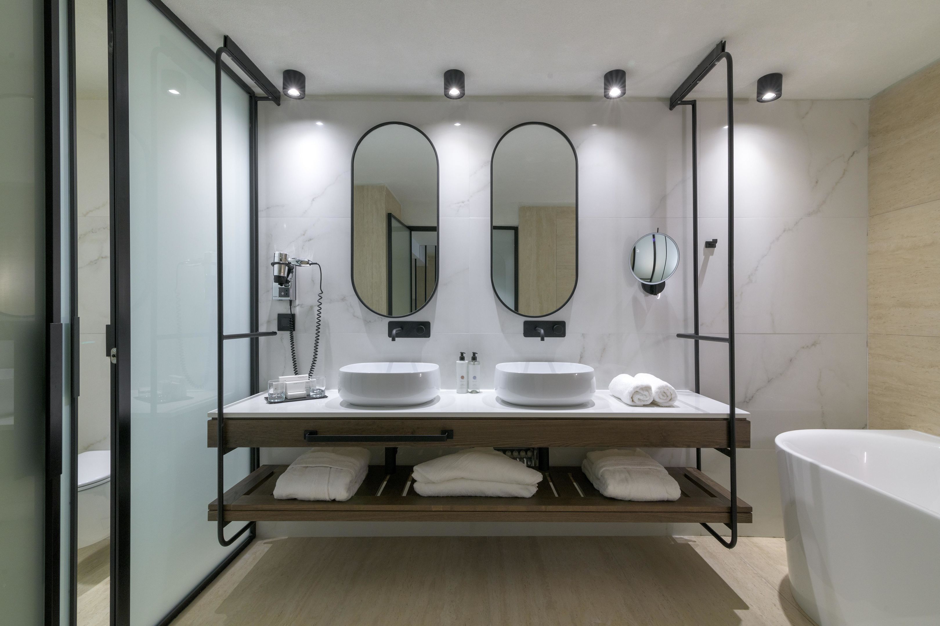 Un baño moderno con dos lavamanos, una bañera grande y una cabina de ducha de vidrio.