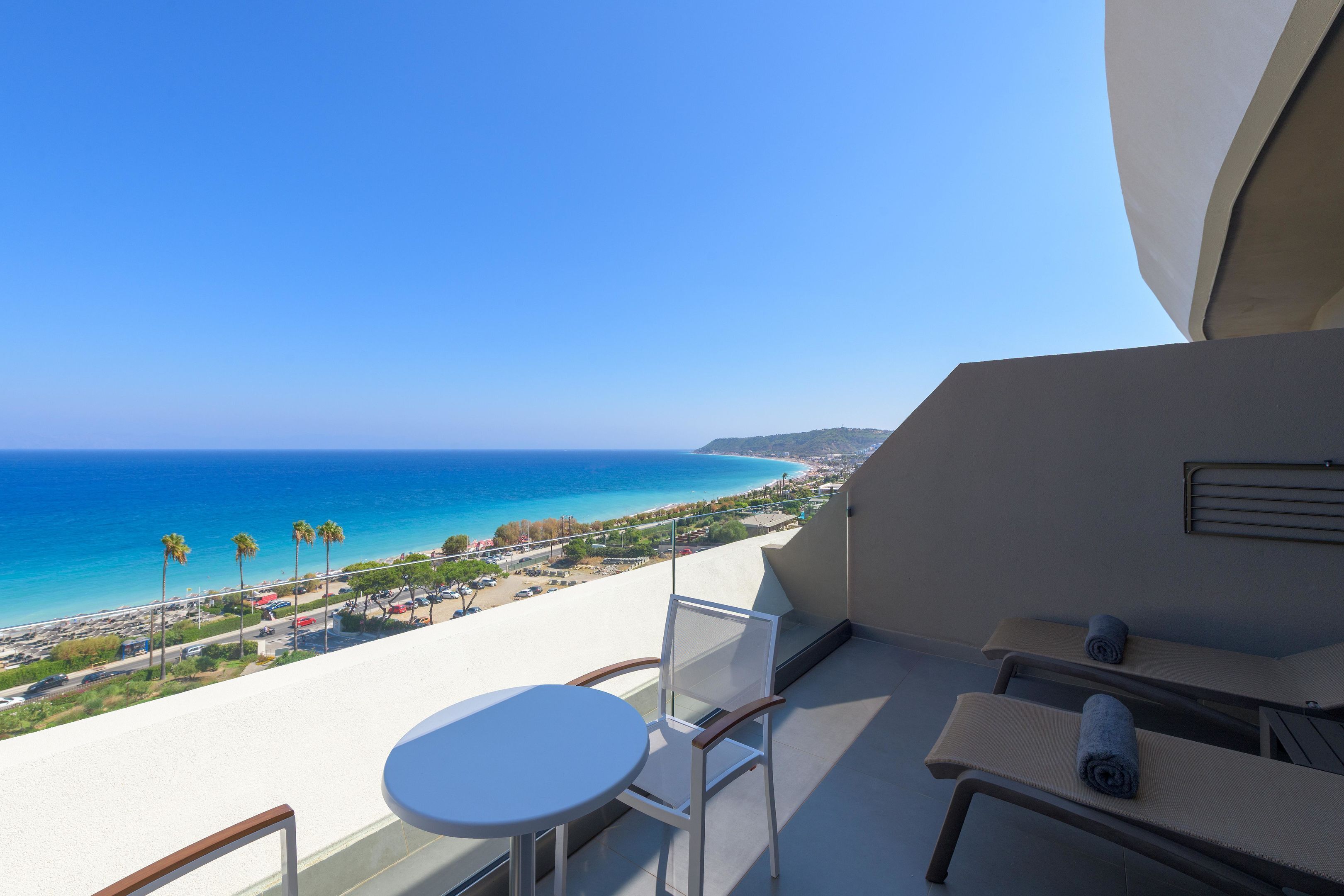 Un balcón con vista al mar, una mesa y dos sillas.