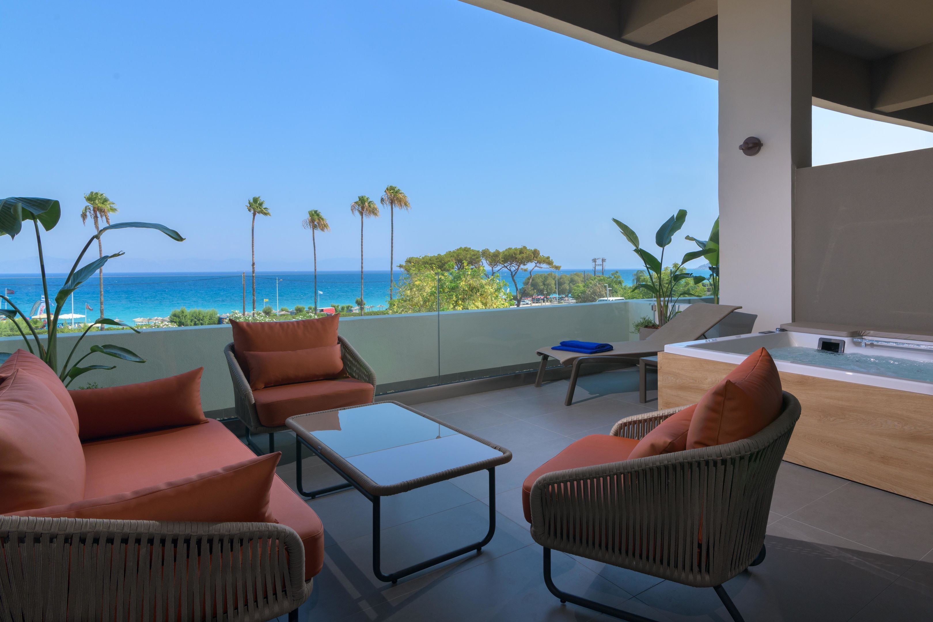 A balcony with wicker furniture, a hot tub, and a view of the ocean.