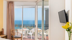 A hotel room with a balcony, a bed, a TV, and a vase with flowers. - Relaxia Beverly Park (San Bartolomé de Tirajana)