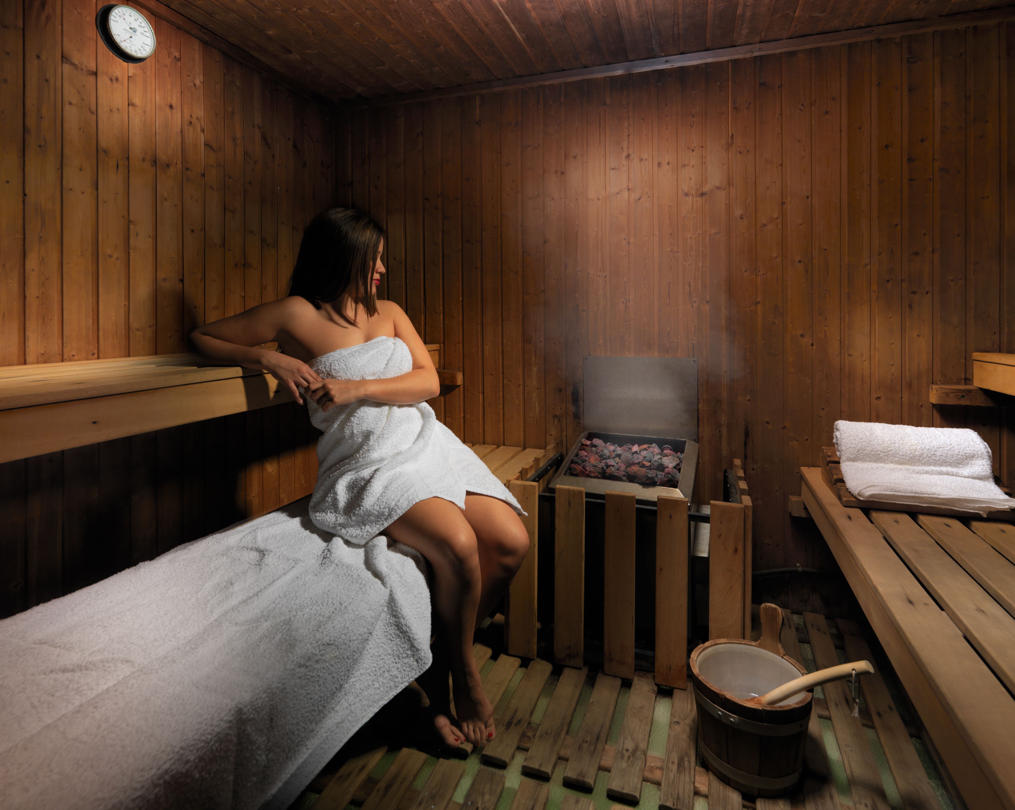 Een sauna met houten banken, een bank met een handdoek en een emmer met een houten handvat.