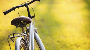 Una bicicleta estática con asiento y manubrio, ubicada sobre una superficie cubierta de césped.