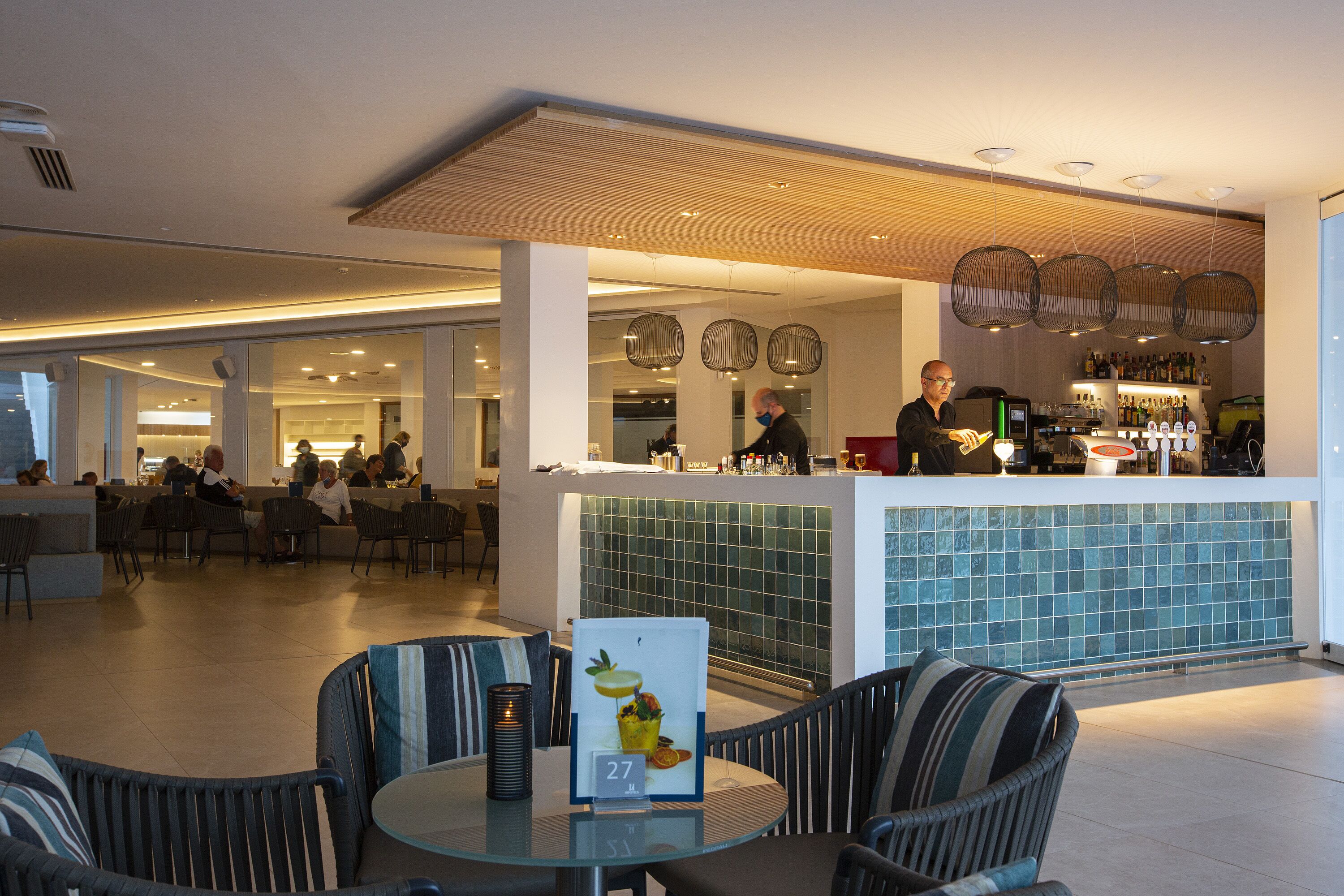Un vestíbulo de hotel moderno con zona de bar, asientos y un salpicadero de azulejos.