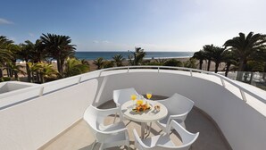 A terrace with a table and chairs, overlooking a beach and palm trees. - Hipotels La Geria (Tías)