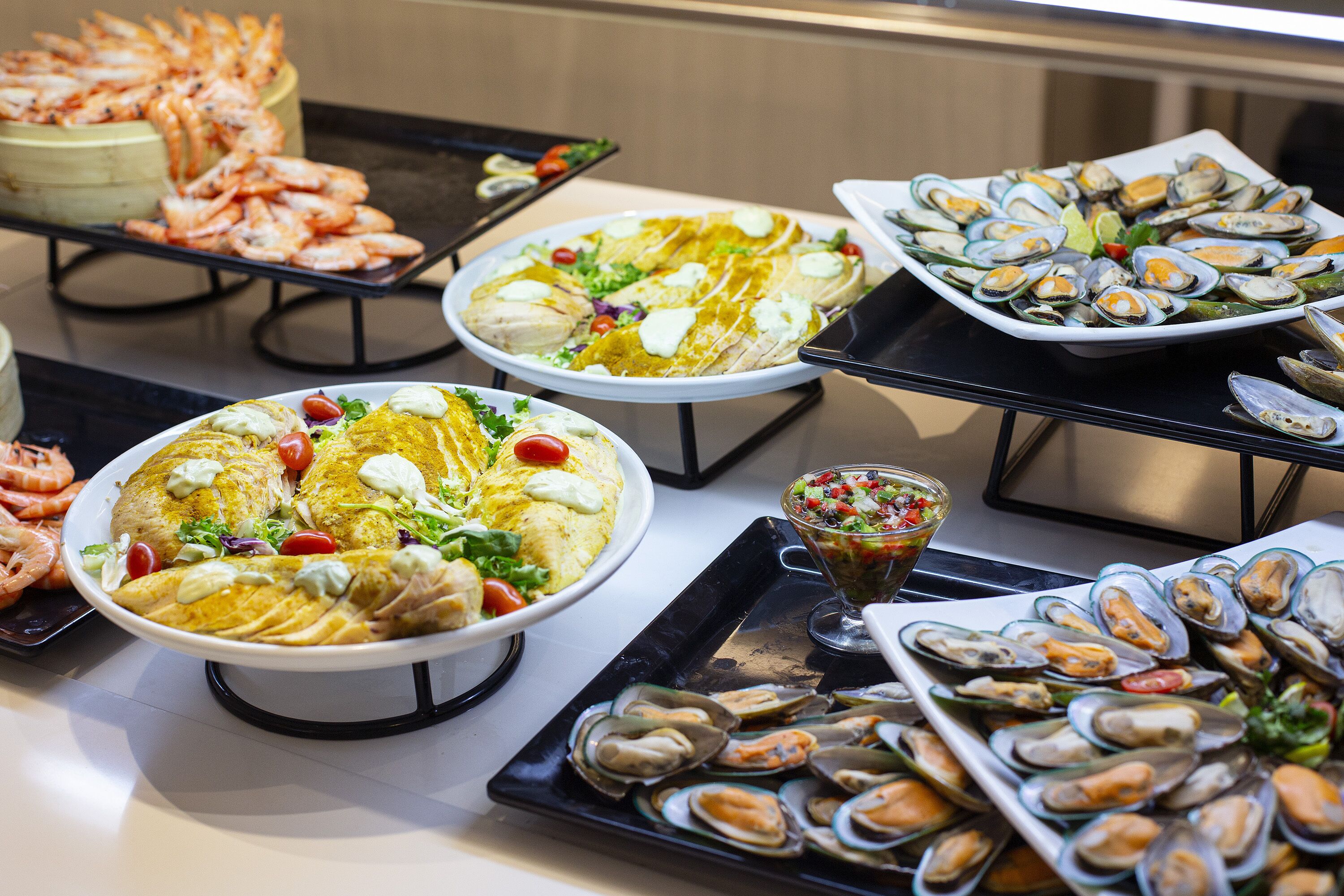 Un buffet proposant divers plats de fruits de mer, notamment des crevettes, des huîtres et une salade.