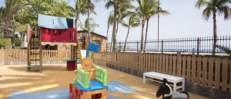 A playground with a slide, climbing structures, and a swing set.