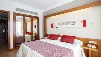 A hotel room with a bed, a bedside table, a mirror, and a wardrobe.