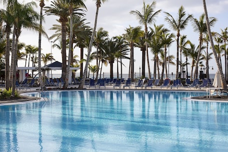 Una piscina al aire libre, sillones reclinables de piscina