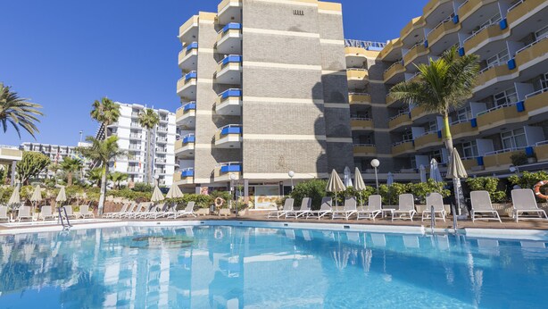 Un hotel con zona de piscina, varios balcones y palmeras.