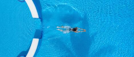 An aerial view of a swimming pool with clear blue water and a swimmer in the center.