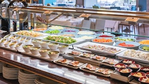Un bufé con diferentes opciones de comida, incluyendo ensaladas, carnes y quesos, presentados en cuencos y bandejas.