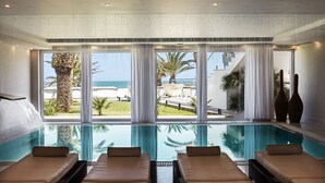 A poolside area with lounge chairs and a view of the ocean. - Mitsis Selection Rinela (Hersonissos)