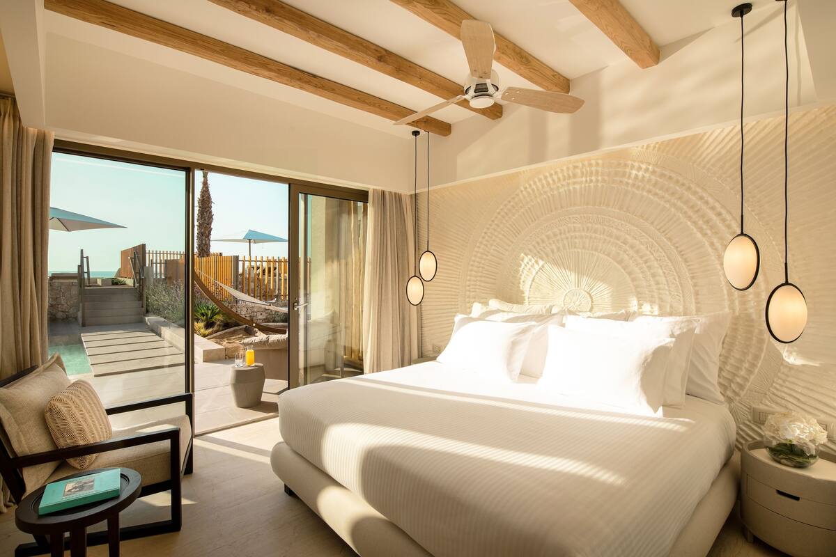 Une chambre spacieuse avec un grand lit, un ventilateur de plafond et une vue sur une piscine et un espace extérieur.