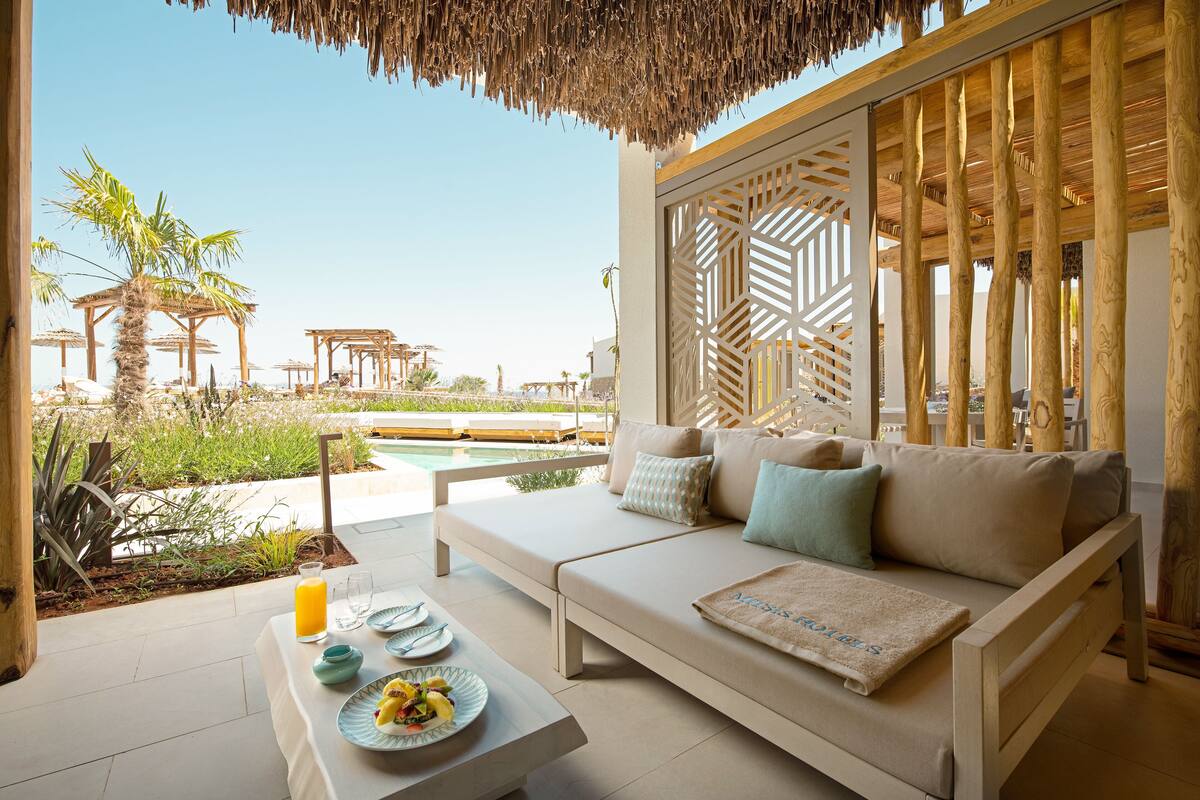 Un espace extérieur accueillant, aménagé avec un canapé et une table, et offrant une vue sur une piscine et un jardin.