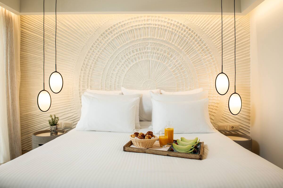 Une chambre d’hôtel dotée d’un grand lit, d’un plateau avec des articles pour le petit-déjeuner et d’un décor de plafond original.