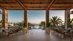 A covered outdoor seating area with a view of the sea. - Mitsis Selection Rinela (Hersonissos)