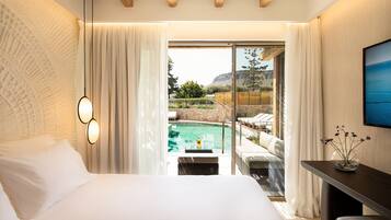 Un dormitorio con una cama grande, vistas a una piscina y un comedor con mesa y sillas.