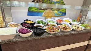 A buffet counter with various food items and a scenic painting in the background. - Pigale Beach Resort (Kusadasi)