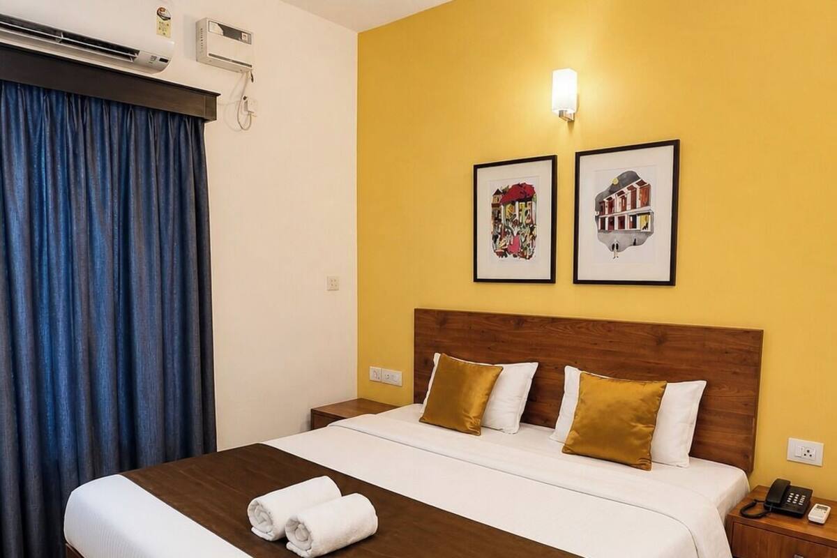 Una habitación de hotel con una cama grande, una mesita de noche con teléfono y dos cuadros en la pared.