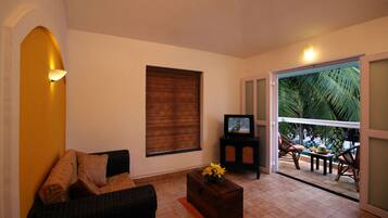 Una sala de estar con un sofá, una mesita con un florero, un televisor y una ventana con persianas.
