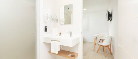 A modern bathroom with a white vanity, a mirror, and a shower area.