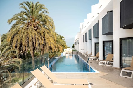 Una piscina al aire libre, sillones reclinables de piscina