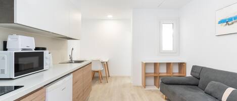 A compact kitchen with a microwave, dishwasher, and a small dining area with a table and chairs.