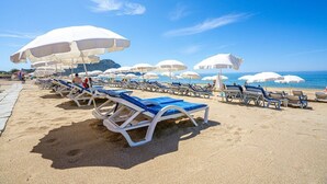 A beach with rows of sun loungers and white umbrellas, a clear blue sky, and the sea in the background. - Blue Star Hotel Alanya (Alanya)