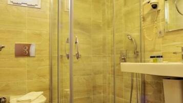 A modern bathroom with a glass-enclosed shower, a toilet, and a sink.