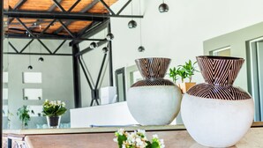 Un interior moderno con un espejo grande que refleja una habitación con techo de madera y lámparas colgantes.