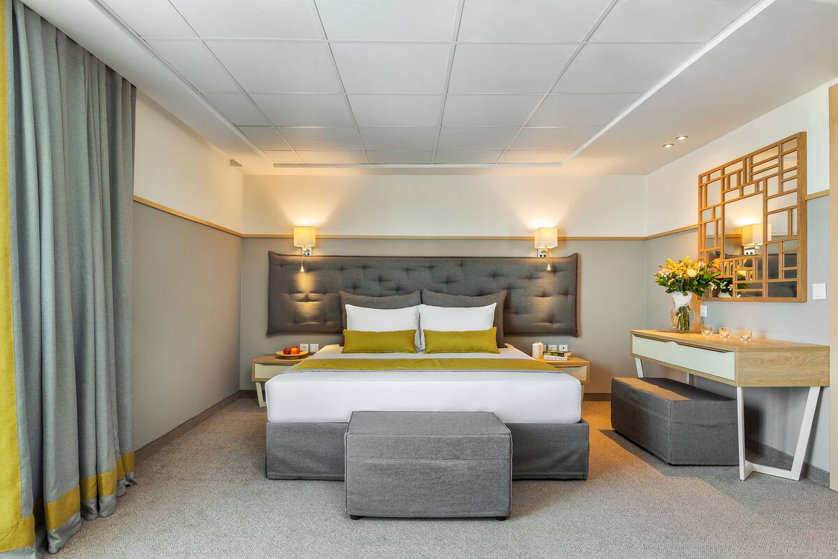 Ein modernes Hotelzimmer mit einem großen Bett, Nachttischen, einem Schreibtisch und einer kleinen Sitzecke.
