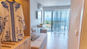 Una sala moderna con un sofá, un televisor montado en la pared y un balcón con vistas.