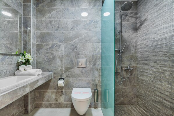 A modern bathroom with a marble tile shower, a glass-enclosed shower, a toilet, and a sink with a marble countertop. - Hotel Kriopigi (Kassandra)