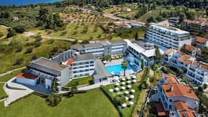Un hotel moderno con piscina, varios balcones y vista al mar.