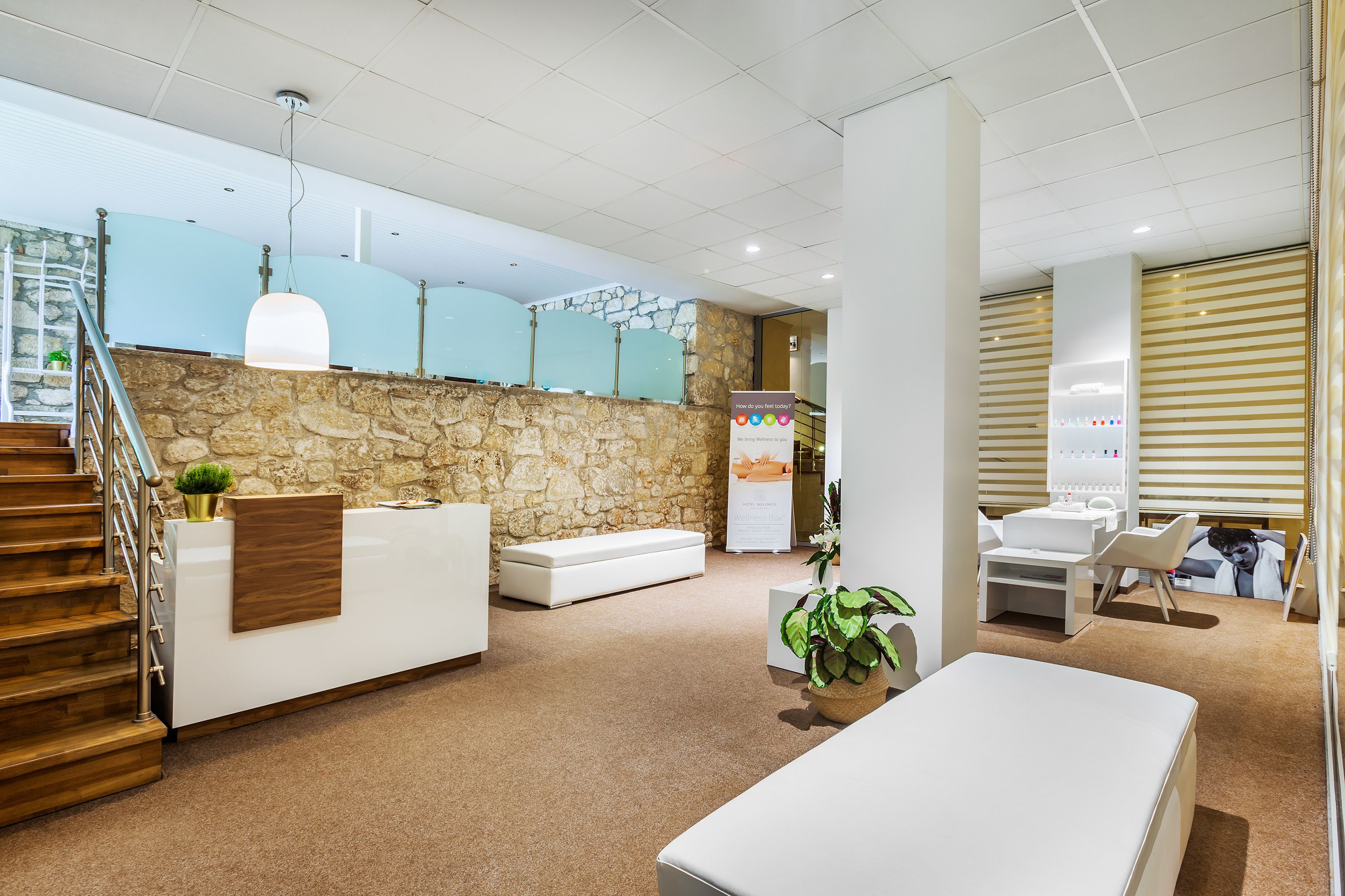 Zona de recepción con pared de piedra, escalera de madera y mostrador de recepción.
