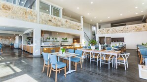 Un comedor amplio y moderno con techos altos y detalles de piedra, que cuenta con varias mesas y sillas.
