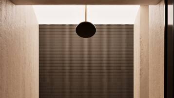 Un baño moderno y minimalista con pared de ducha revestida de azulejos, una lámpara colgante sencilla y un diseño limpio y despejado.