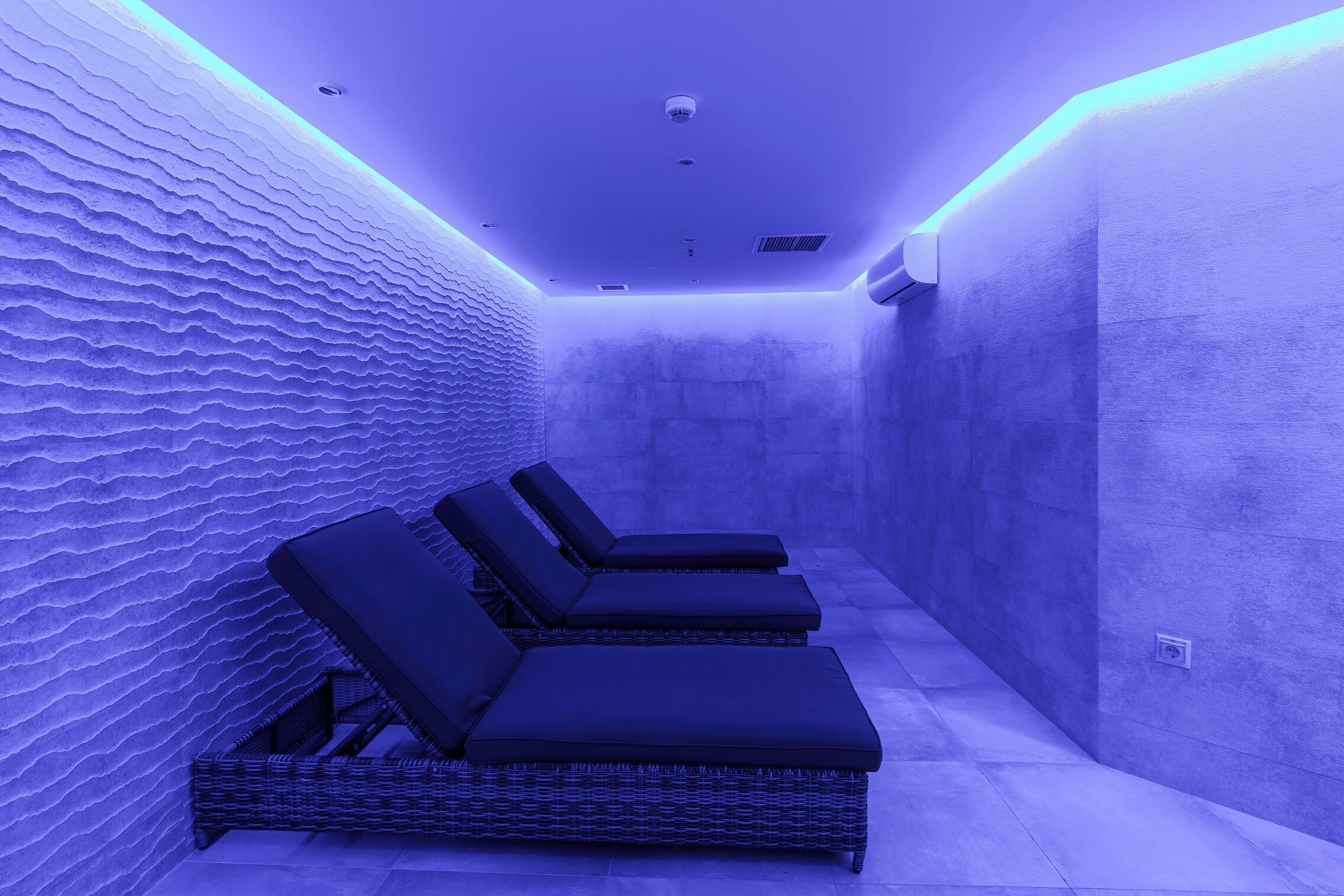 A spa area with three lounge chairs and a textured wall.