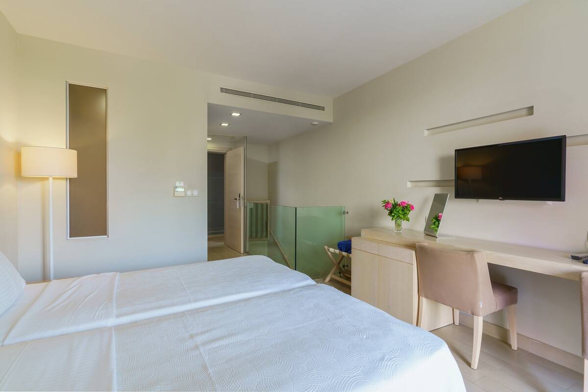 A hotel room with a bed, a desk, a chair, a television, and a mirror.