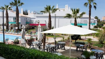 A poolside area with lounge chairs, umbrellas, and tables.