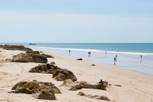 Una playa cerca, sillas reclinables de playa, sombrillas
