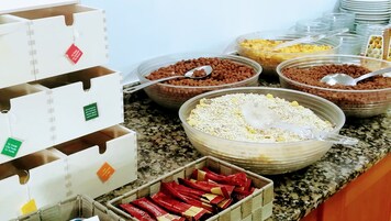 A buffet setup with various food items in bowls and containers, including cereals, grains, and snacks.