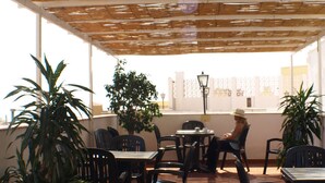 An outdoor patio with tables and chairs, surrounded by potted plants. - Hotel Kristal (Torremolinos)