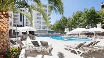 Una piscina al aire libre, sombrillas, tumbonas