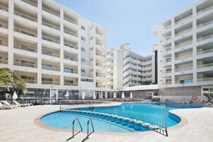 Ett poolområde med flera nivåer av balkonger, solstolar och parasoller.