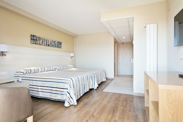 A modern hotel room with a large bed, a desk, a flat-screen TV, and a painting on the wall.